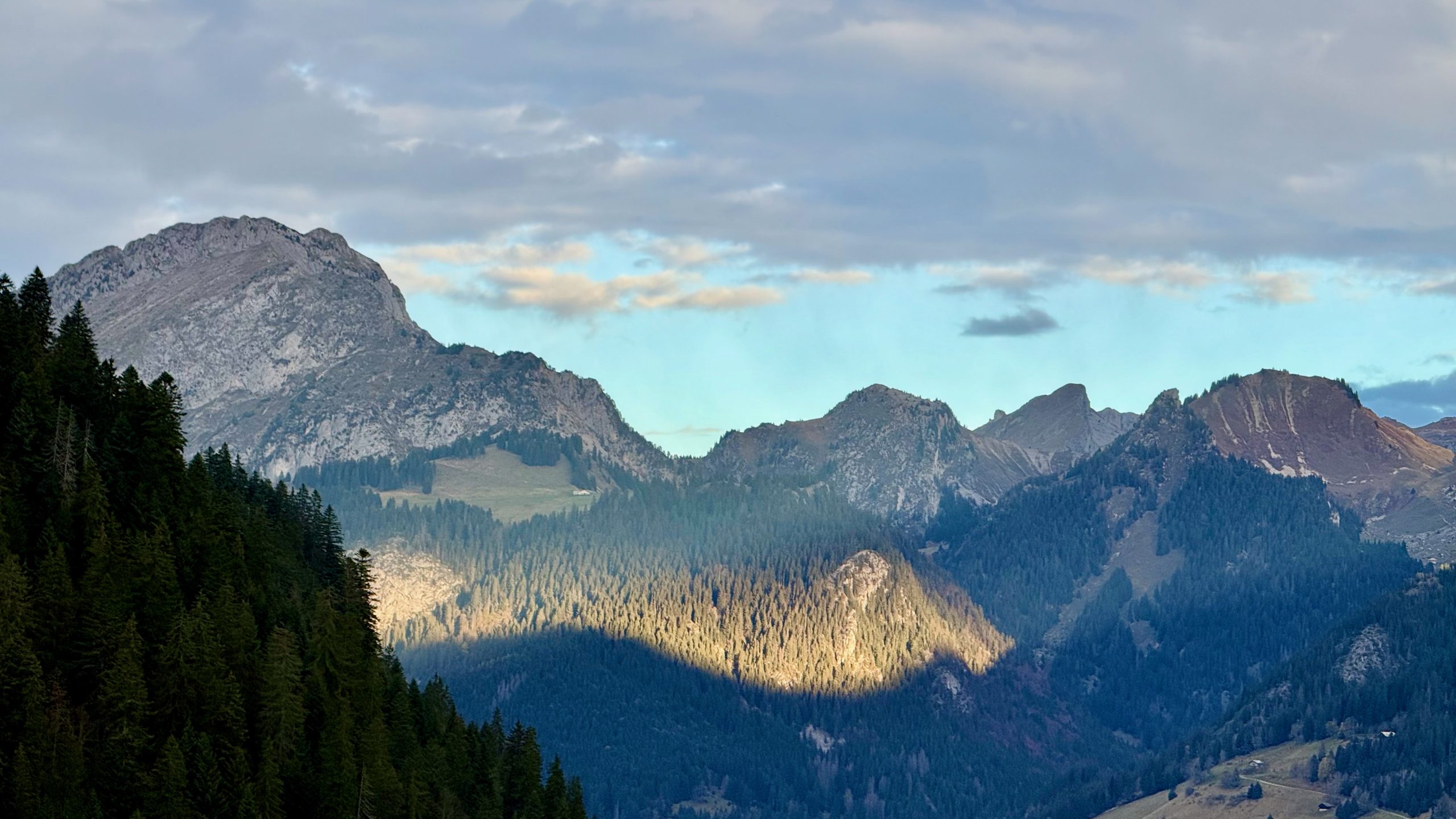 A band of sunshine lighting up a mountain view through the shadows
